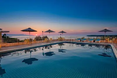 a pool with chairs and umbrellas on top of a hotel at Creta Vitalis in Kalathas