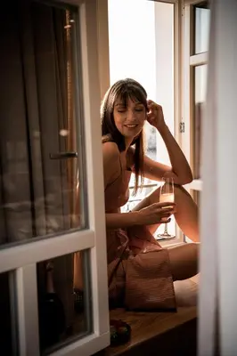 a woman sitting on a window sill with a glass of wine at Divino Suites Chania in Chania Town