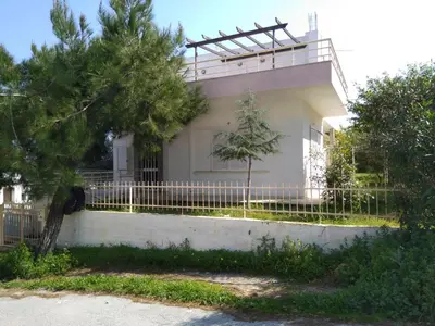 a white house with a fence and a tree at Thanasis Villa in Kounoupidhianá
