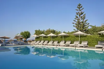 a swimming pool with lounge chairs and umbrellas at Atlantica Amalthia Beach Hotel - Adults Only in Agia Marina Nea Kydonias