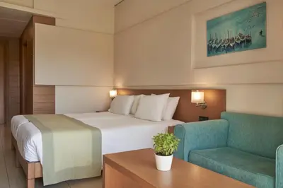 a hotel room with a bed and two chairs at Atlantica Amalthia Beach Hotel - Adults Only in Agia Marina Nea Kydonias