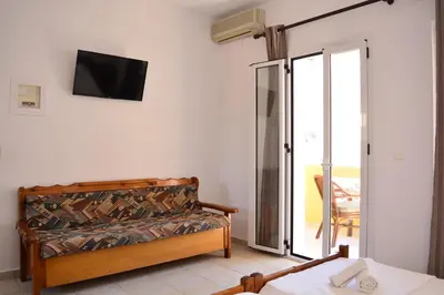 a room with a bed and a tv on the wall at Raph's Studios-Apts By The Sea in Agia Marina Nea Kydonias