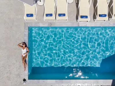 an overhead view of a woman sitting next to a swimming pool at Athina Suites Luxury Suites Near The Sea Platanias in Plataniás