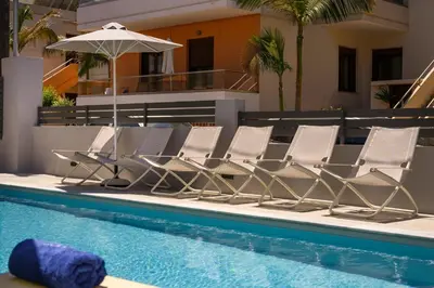 a group of chairs and an umbrella next to a swimming pool at Athina Suites Luxury Suites Near The Sea Platanias in Plataniás