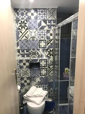 a bathroom with a toilet and a tiled wall at Odyssey Apartment in Palaiochóra