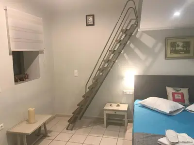 a bedroom with a spiral staircase next to a bed at Odyssey Apartment in Palaiochóra