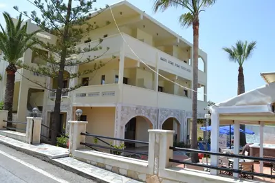 a building with palm trees in front of it at Sunny Suites in Maleme