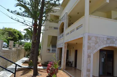 a building with a palm tree in front of it at Sunny Suites in Maleme