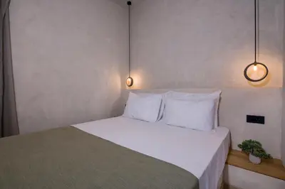 a bedroom with a bed with white pillows and two lights at Cretan Berry Sarpaki in Chania Town
