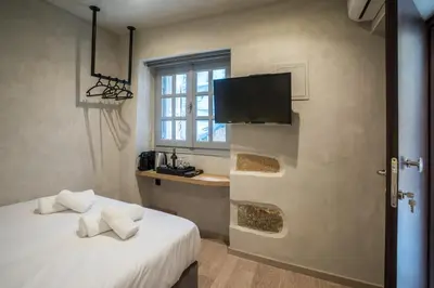 a bedroom with a bed and a tv and a window at Cretan Berry Sarpaki in Chania Town