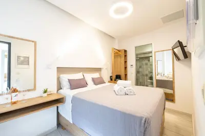 a white bedroom with two towels on a bed at Cretan Berry Portou in Chania Town