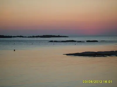 a sunset over the ocean with rocks in the water at Horio House in Límni