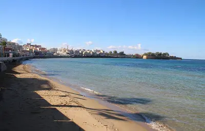 a beach with the ocean and buildings in the background at Marias Studios in Chania Town