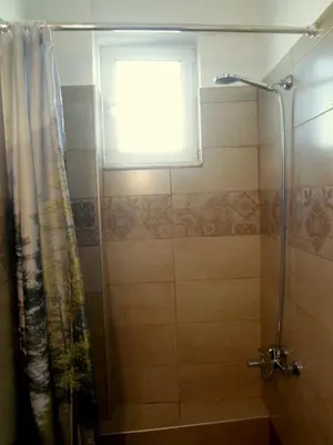 a bathroom with a shower curtain and a window at Marias Studios in Chania Town