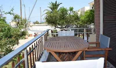a wooden table and chairs on a balcony at Modern Apartment with Garden in Kissamos