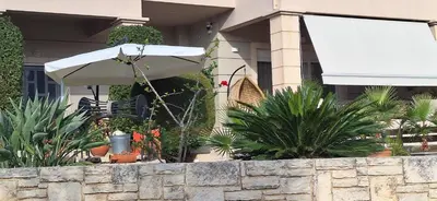 a white umbrella in front of a building with plants at Modern Villa in Chania in Perivólia