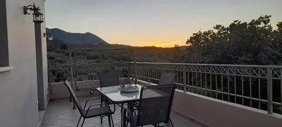 a table and chairs on a balcony with the sunset at 