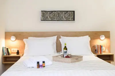 a bed with two white pillows and a bottle of wine at Casa Teresa | Near Sandy Beach in Chania Town