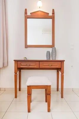 a wooden dressing table with a stool and a mirror at Roubini Apartments in Falasarna