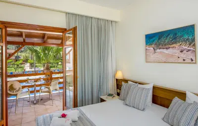 a hotel room with a bed and a table and chairs at Omega Platanias in Plataniás