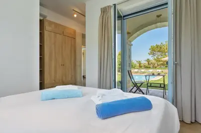 a bedroom with a white bed with blue pillows on it at Calma Seaside Villa in Kalyves