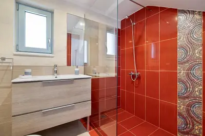 a bathroom with a sink and a shower with red tiles at Calma Seaside Villa in Kalyves