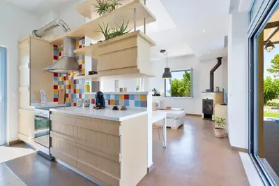 a kitchen with a counter and a living room at Calma Seaside Villa in Kalyves