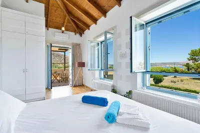 a bedroom with a bed and a large window at Calma Seaside Villa in Kalyves