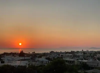 a sunset over the ocean and a city at NeSo - Peter's Flat steps to Beach with Great Views in Kolymvari