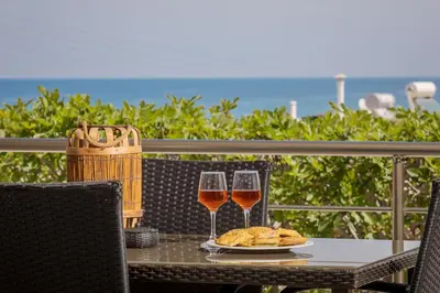 a table with two glasses of wine and a plate of food at NeSo - Peter's Flat steps to Beach with Great Views in Kolymvari
