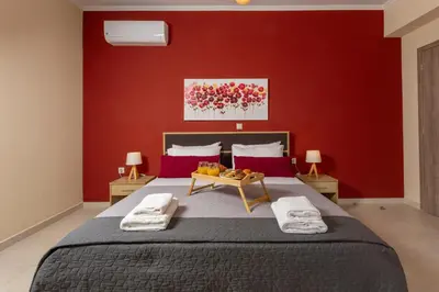 a bedroom with a large bed with red walls at NeSo - Peter's Flat steps to Beach with Great Views in Kolymvari