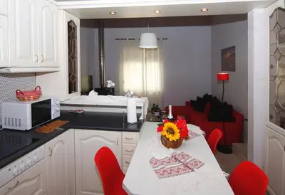 a kitchen with a table and red chairs and a living room at Maria's house in front of the beach in Chania Town