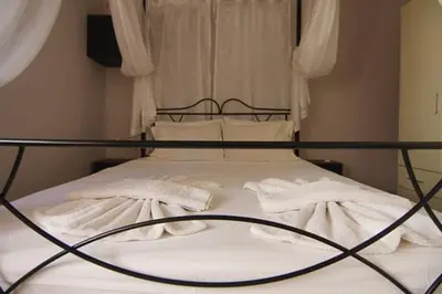 a bed with white sheets and pillows on it at Maria's house in front of the beach in Chania Town