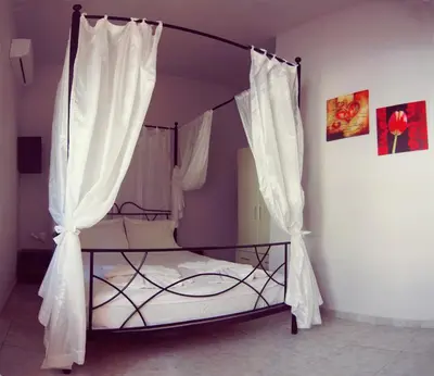 a bedroom with a canopy bed with white curtains at Maria's house in front of the beach in Chania Town