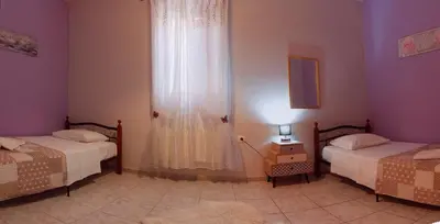 a bedroom with two beds and a dresser with a window at Maria's house in front of the beach in Chania Town