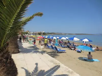 a group of people sitting on a beach with umbrellas at Maria's house in front of the beach in Chania Town