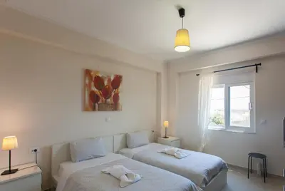 two beds in a white room with a window at Paleochora Houses N2 in Palaiochóra