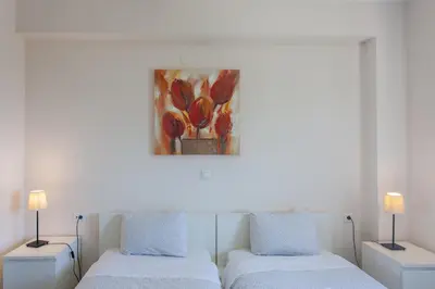 two beds in a room with a painting on the wall at Paleochora Houses N2 in Palaiochóra