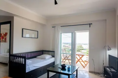 a bedroom with a bed and a table and a balcony at Paleochora Houses N2 in Palaiochóra