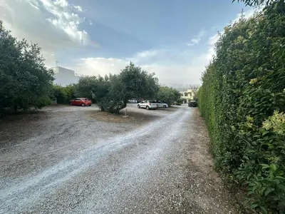 a gravel road with cars parked on it next to a hedge at Rodon Hotel in Chania Town