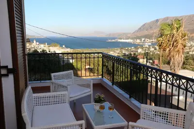 a balcony with white chairs and a table with a view at Chrisas Apartment Chania in Chania Town