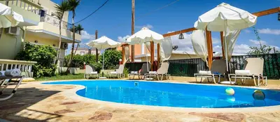 a pool with chairs and umbrellas next to a building at Irinoula Dreams in Kolymvari