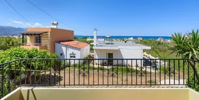 a balcony with a view of a house and the ocean at Irinoula Dreams in Kolymvari