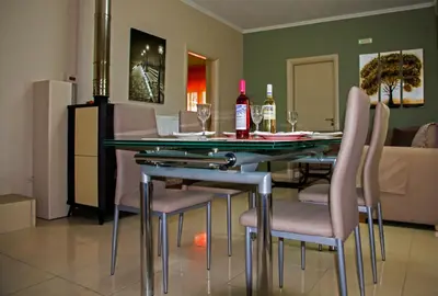 a dining room with a glass table and pink chairs at Lydia's Apartment in Stílos