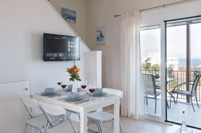 a white dining room with a white table and chairs at Like Home in Agia Marina Nea Kydonias