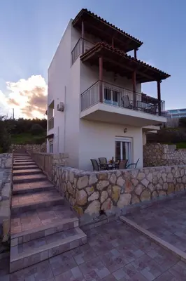 a house with a balcony and a stone wall at Like Home in Agia Marina Nea Kydonias