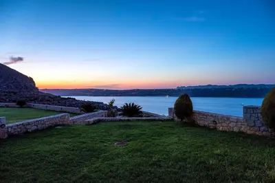 a sunset over the water with a stone wall at Margarita Apt - Amazing Relaxing View in Megála Khoráfia