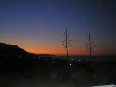 a sunset with three pine trees on a hill at Panoramic Balos Sea View House in Kissamos