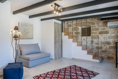 a living room with a chair and a staircase at Trialonia Luxury Villa in Kissamos