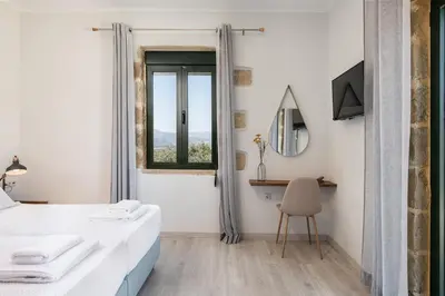 a bedroom with a bed and a desk and a window at Trialonia Luxury Villa in Kissamos